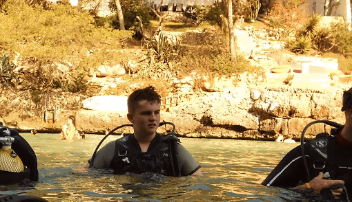 Beau scuba diving in Cala d'or, at the water's surface with coastal cliffs behind